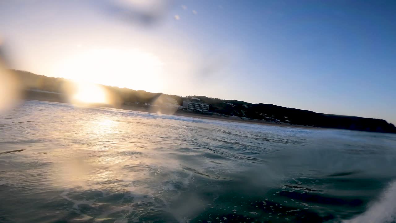 surfista surfeando olas oceánicas tropicales atacando el labio con un enorme amanecer en el fondo