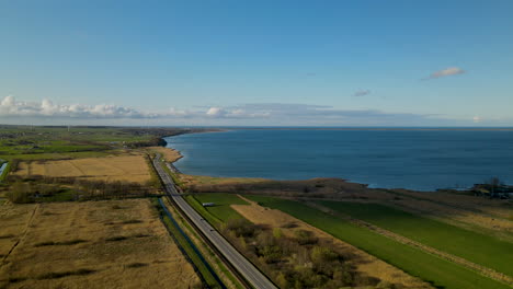 Vista-Aérea-Que-Muestra-La-Carretera-Marítima-Con-La-Conducción-De-Automóviles-Rodeados-De-Campos-Agrícolas-En-Puck-Durante-El-Día-Soleado,-Polonia