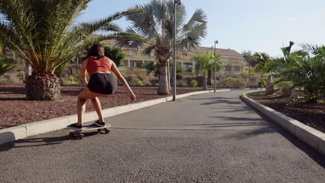 Cámara-Lenta-Retrata-Una-Escena-Fascinante:-Una-Joven-Montando-Hábilmente-Su-Longboard-Junto-A-La-Playa-Y-Las-Palmeras