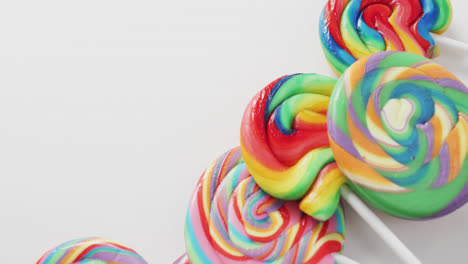 video of rows multicoloured lollipops on white background