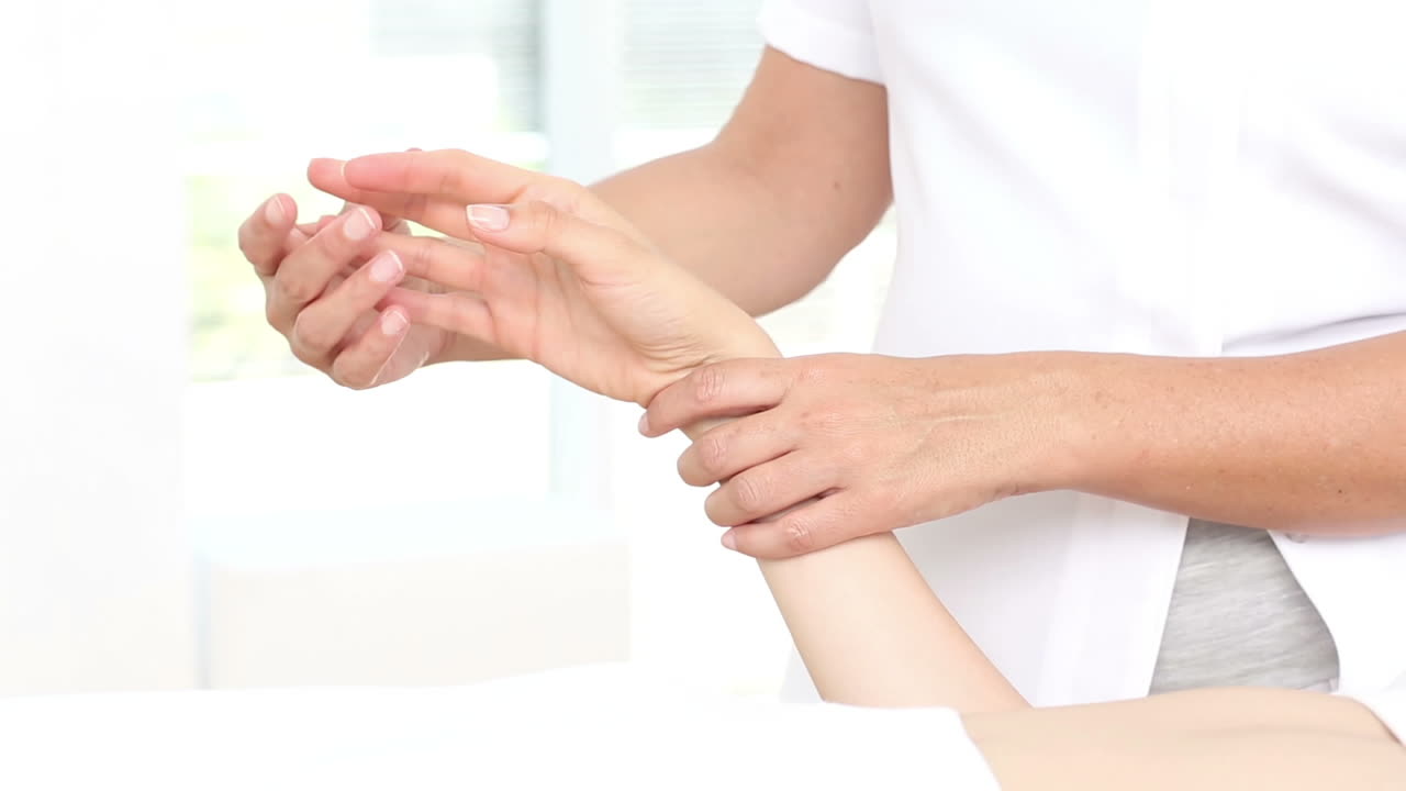 물리 치료사 가 환자 의 손 을 검사 하고 있다