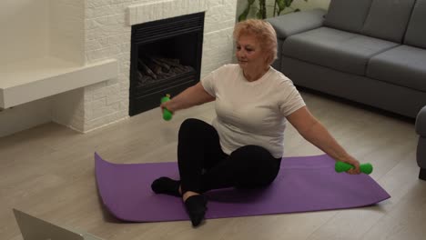 deporte en casa. mujer mayor activa haciendo ejercicios de estiramiento de calentamiento frente a una computadora portátil, entrenando con tutoriales en línea