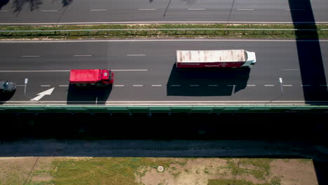 Aerial-top-down---tracking-truck-moving-on-expressways---multi-lane-connections-of-agglomerations,-modern-and-safe-roads---maintaining-supply-chain-and-logistics