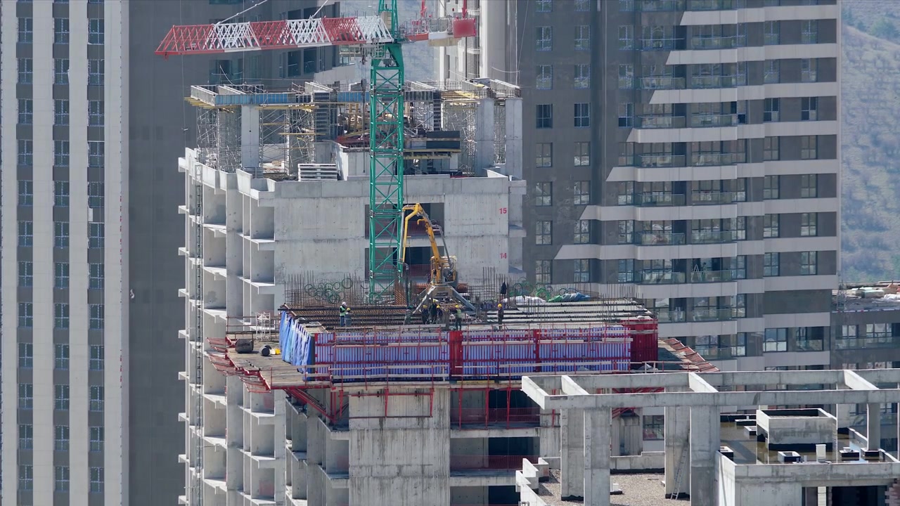 高層ビルでコンクリートポンプを操作する建設作業員