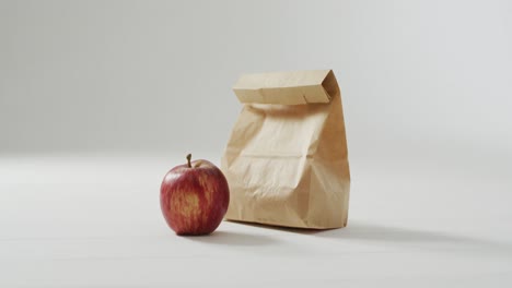 animation of paper lunch bag an fruits on blue background