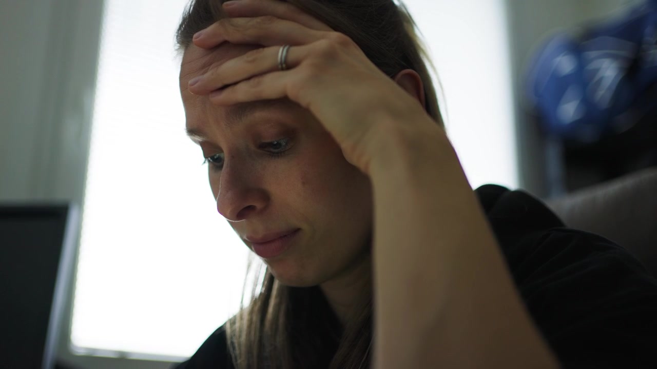Mulher estressada segurando a cabeça enquanto trabalha na mesa em ambiente interno