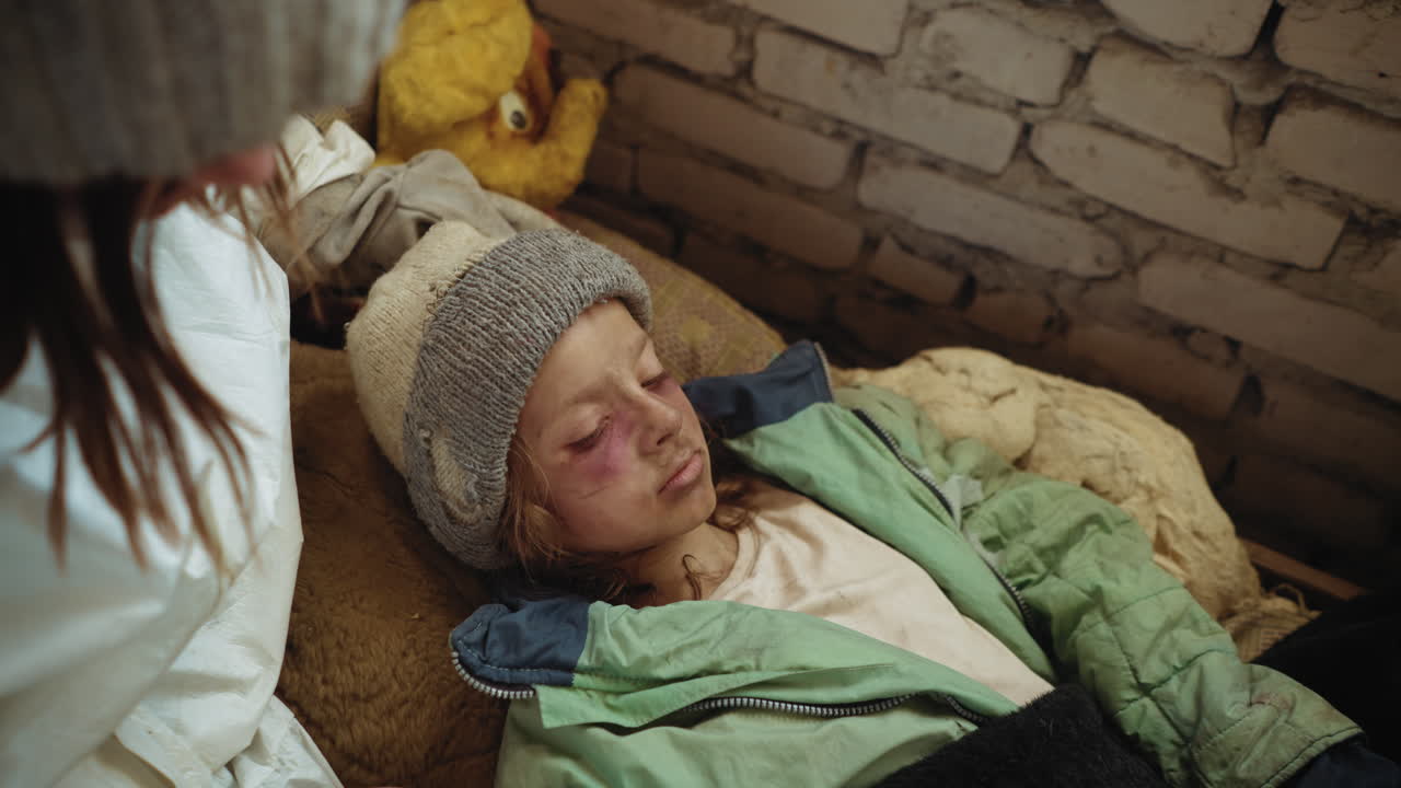 Close up of injured refugee girl lying unconscious on old mattress inside abandoned building, bruises marking her pale weak face symbolising despair and fragile survival after post apocalypse