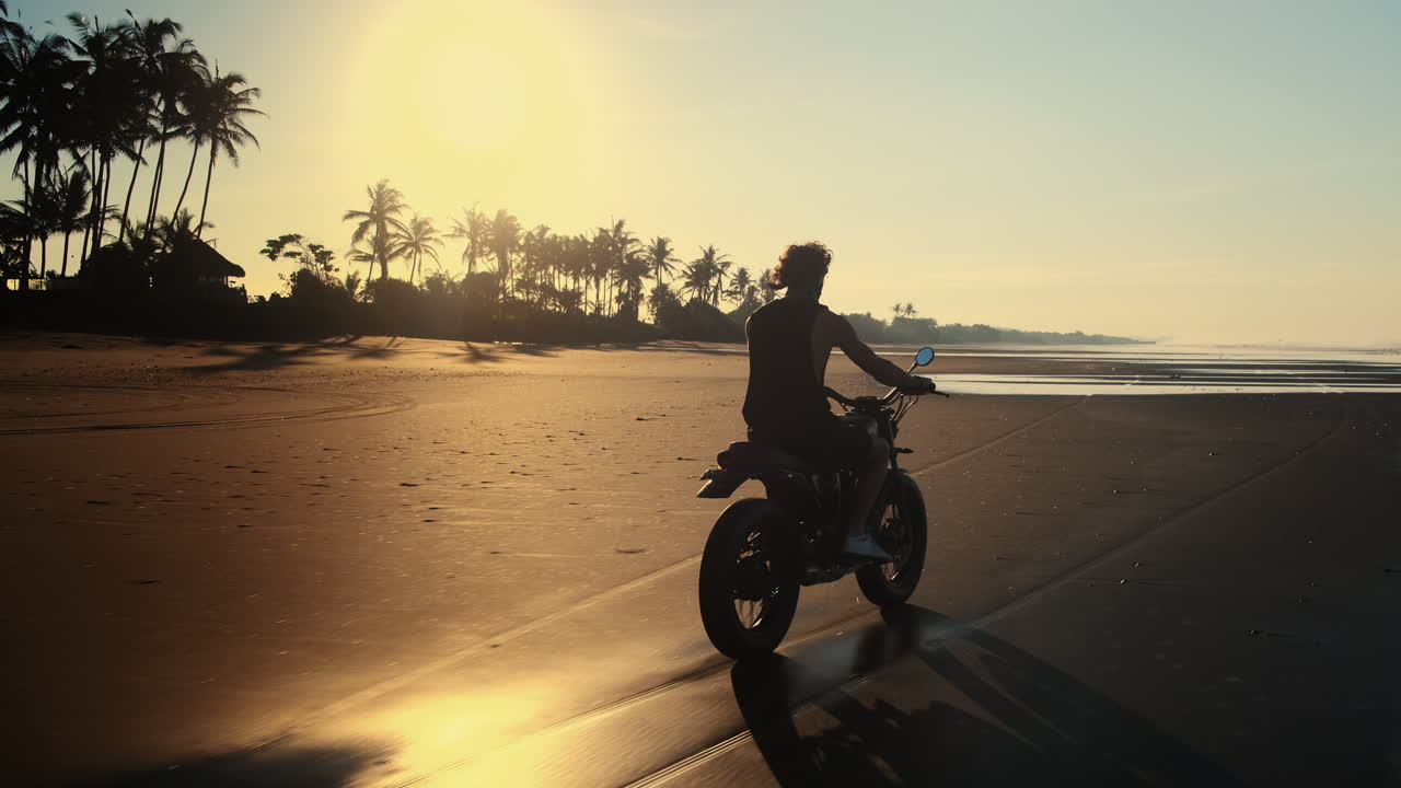 Man Riding Motorcycle on a Beach at Sunrise