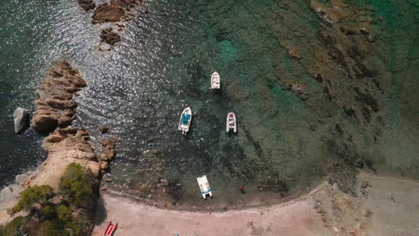 top view of moored sailing boats near rocky coastline of serene ocean in sardinia, italy