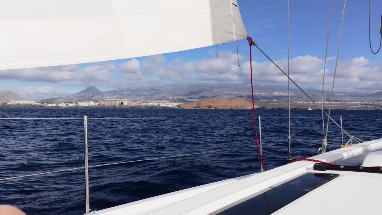 Segelboot gleitet über ruhiges blaues Wasser vor der Kulisse friedlicher Küstenberge, Teneriffa