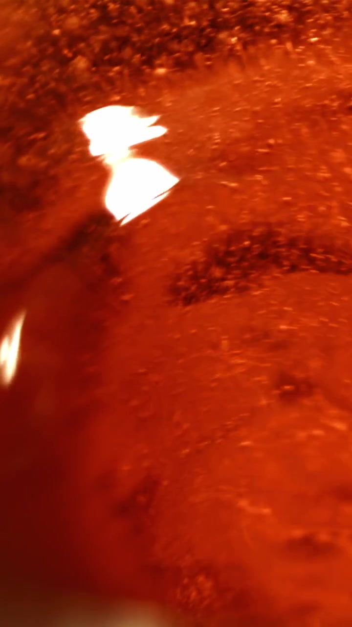 Superficie fluida rossa astratta con riflessi di luce in movimento
