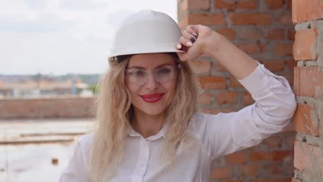 female architect in business attire and a white helmet stands at the construction site