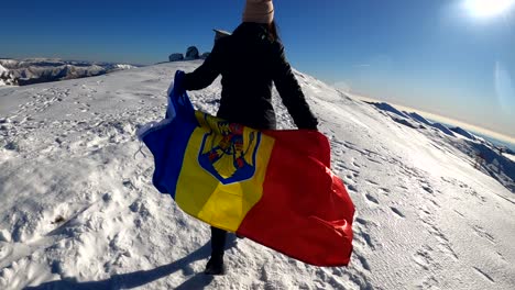 girl running with the romanian flag on top of the bucegi mountains, in romania - slow motion shot