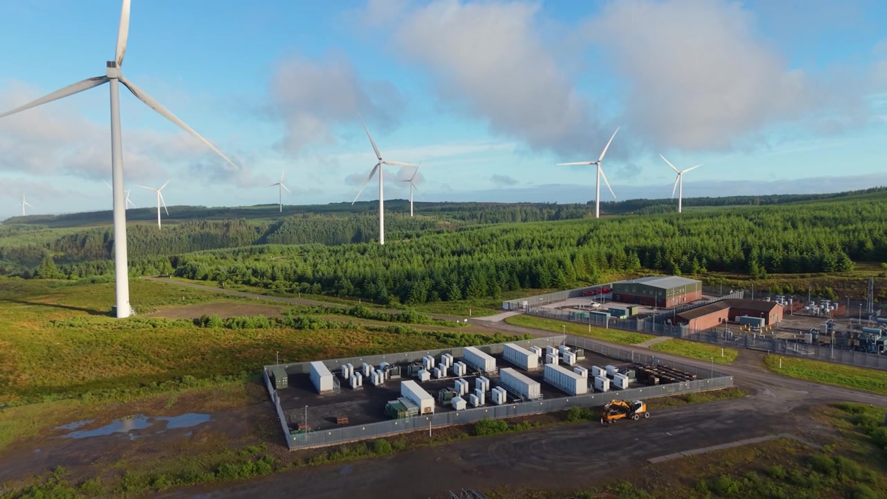Wind Farm and BESS Battery Energy Storage System and Substation near Forest in Wales, UK. Perfect for concepts on green technology, sustainability, and the future of power. Aerial Footage 4K.