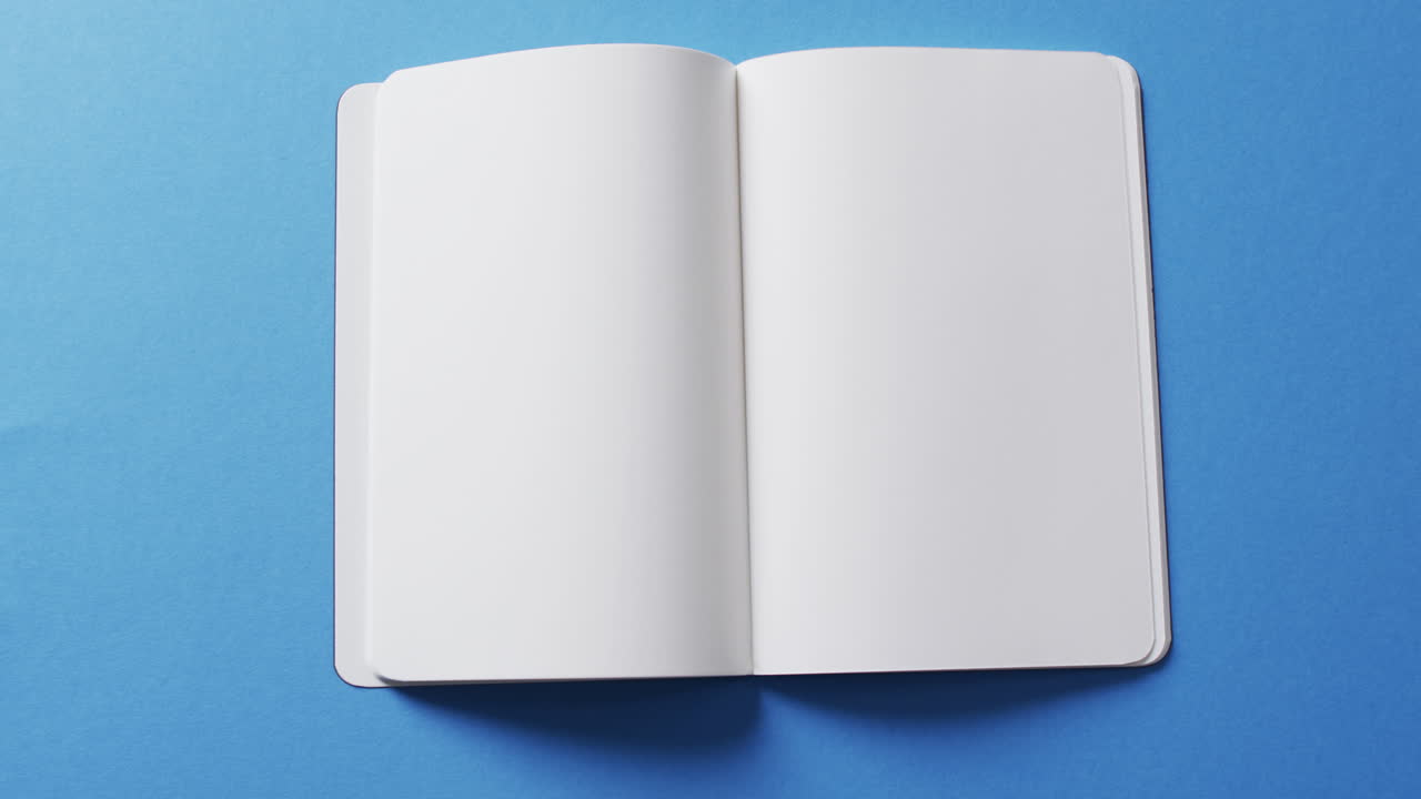 primer plano de un libro en blanco abierto con espacio de copia en un fondo azul en cámara lenta