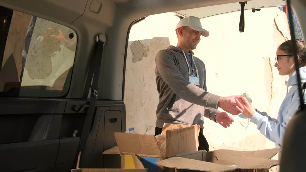 joven voluntario distribuyendo comida de banco y máscaras médicas entre los refugiados del pueblo ucraniano en la calle.