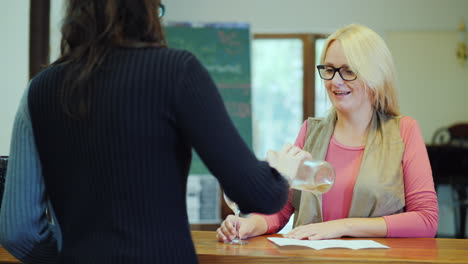 a woman tastes wine in a small winery communicates with the seller