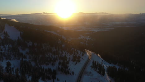 Aerial-View-of-Winter-Sunrise-Above-Rural-Colorado,-Snow,-Forest-and-Empty-Road