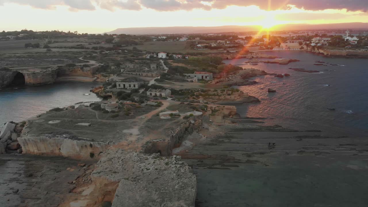 Vista aerea della spiaggia di Punta della Mola con rovine e una casa abbandonate durante un tramonto dorato a Siracusa, Sicilia, Italia