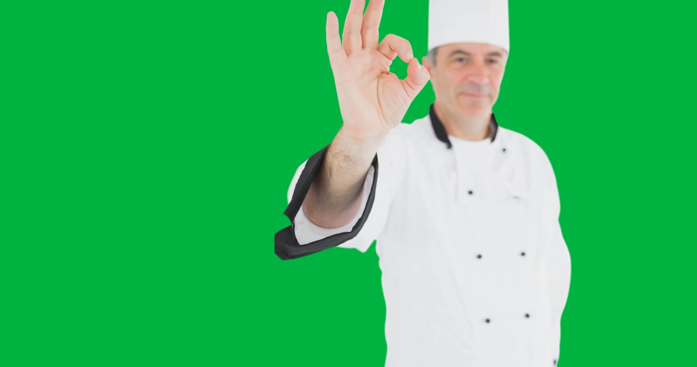 Ritratto di chef maschio caucasico che fa il segno dell'okay su sfondo nero.