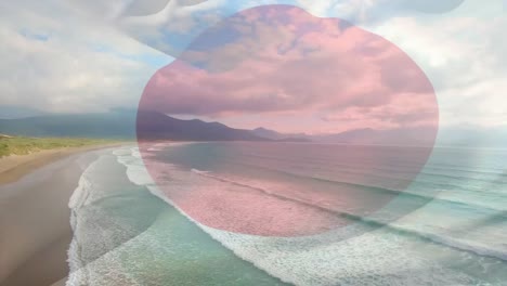 digital composition of waving japan flag against aerial view of the beach and sea waves