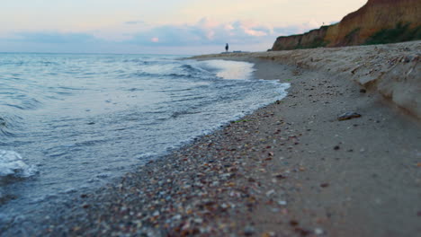 Sea-waves-water-splashing-sand-beach-at-sunrise.-Lonely-woman-walking-beach