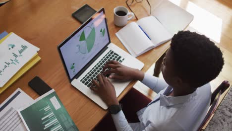 Overhead-view-of-african-american-woman-using-laptop-while-working-from-home