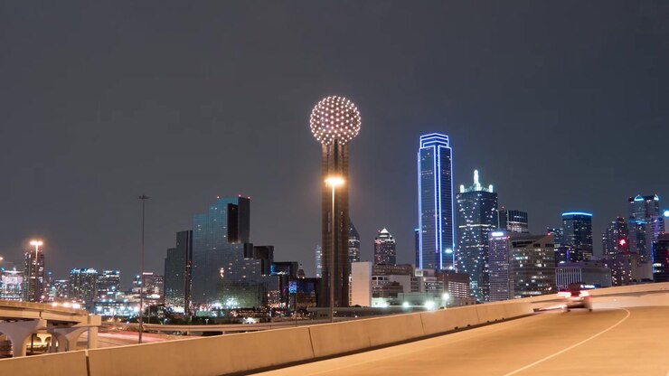 Ripresa cinematografica notturna dello skyline di Dallas, della Reunion Tower e delle scie luminose del traffico autostradale