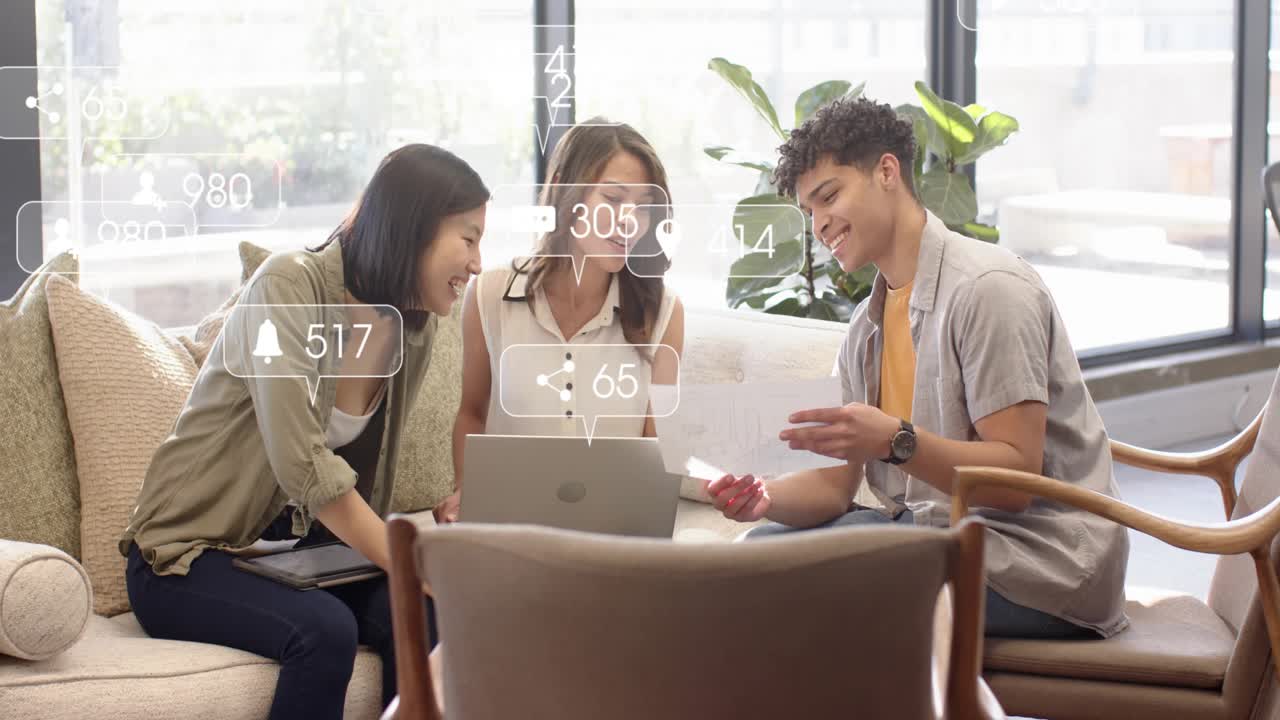 Team of 3 working in lounge man handing paper leaning over laptop reviewing social metrics overlays