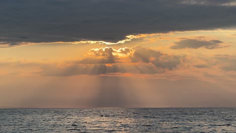 golden sun rays emerge through the clouds over the sea