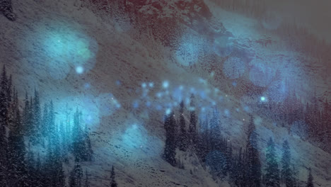 composición digital de manchas brillantes azules de luz contra el paisaje de nieve con montañas y árboles