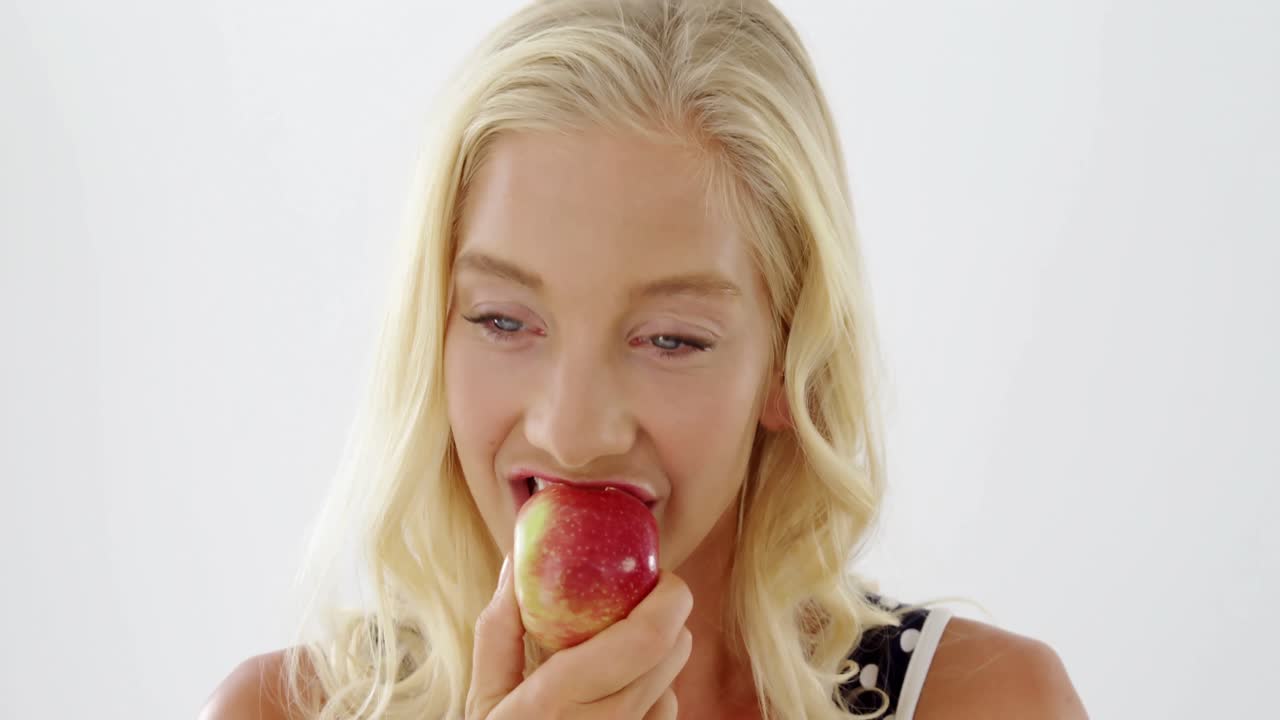 Nahaufnahme einer schönen Frau, die einen roten Apfel isst