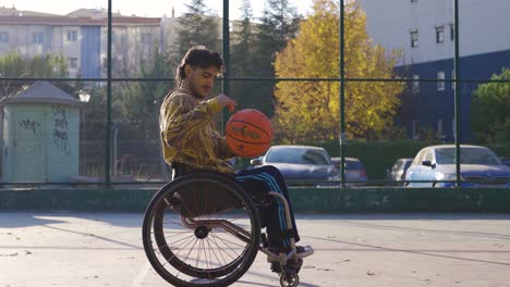 hombre discapacitado en silla de ruedas jugando al baloncesto afuera.