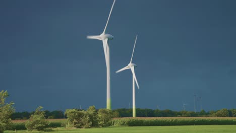 two rotating wind turbine tower above the green landscape