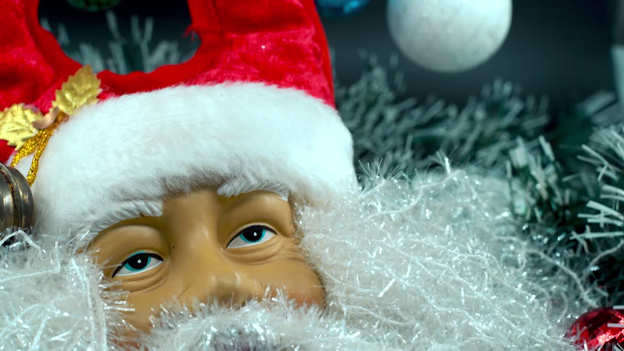 Primo piano dettagliato con ripresa fluida in tilt up, giocattolo di Babbo Natale felice con cappello rosso e campanelle, decorazione natalizia, regali tradizionali delle feste, decorazioni di Capodanno, regali lucidi e colorati, video 4K