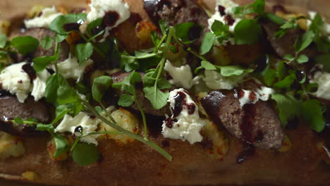 top view of a chef composing a pizza: dripping wine reduction on top of a sausage, potato and mozzarella roman style pizza