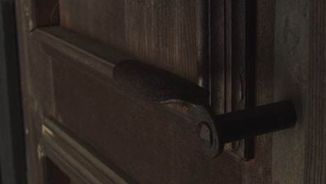 hand tries to open locked iron door handle of old wooden door