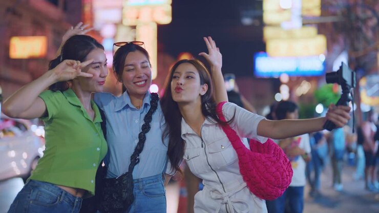 Three friends taking selfies at night in a city