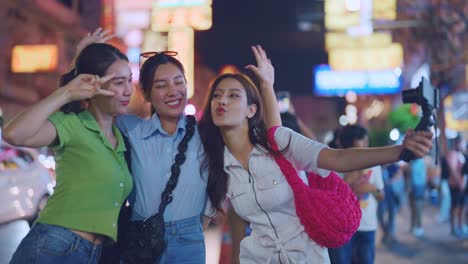 three friends taking selfies at night in a city