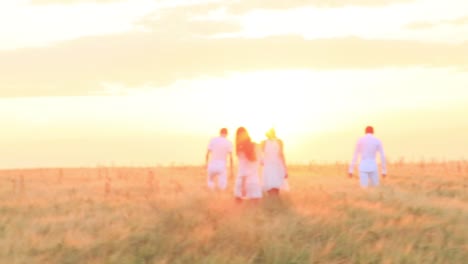 people walking in a wheat field at sunset