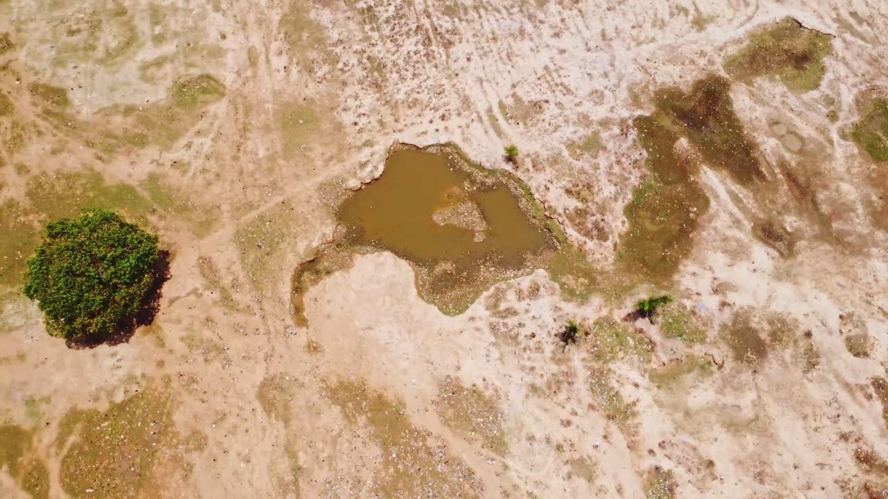 Top down aerial of a small pond in an arid landscape in rural Nigeria, Africa on a sunny day