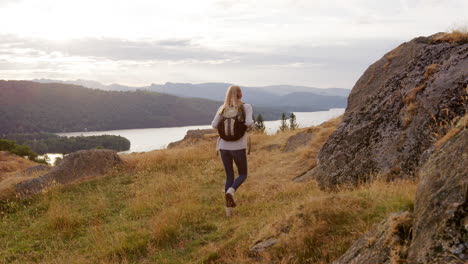 a young adult caucasian woman stops to admire the view during a mountain hike, handheld