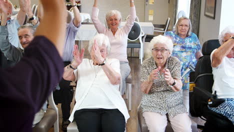 carer leading group of seniors in fitness class in retirement home