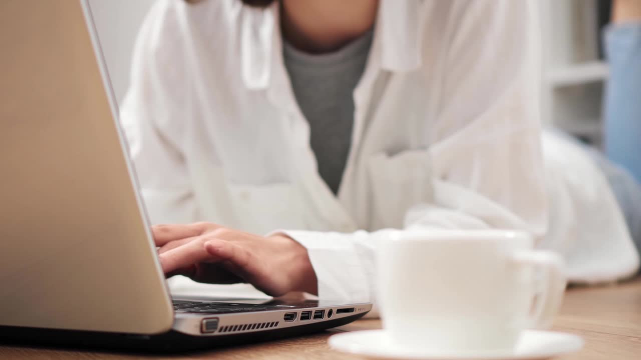 niña tendida en el suelo trabajando en una computadora portátil presionando botones teclas escribiendo texto estudiante