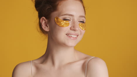 redheaded girl in front of camera on yellow background.