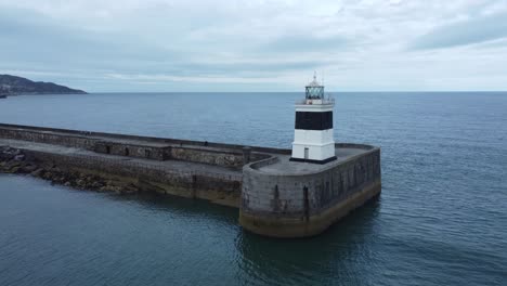 Holyhead-breakwater-lighthouse-longest-concrete-coastal-sea-protection-landmark-aerial-view-low-right-orbit