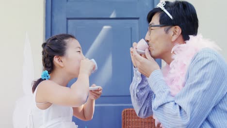 요정 복장을 입은 아버지와 딸이 차 파티를 하고 있습니다.