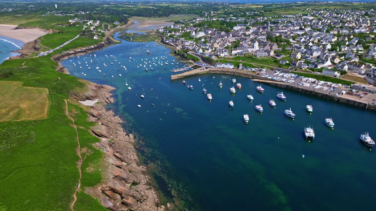 Amazing drone view about the coastal bay of Vieux Port du Conquet with blue seawater, green fields and local commune with anchored yachts, Le Conquet, Brittany, France.