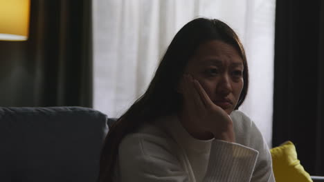 Close-Up-Of-Stressed-Or-Anxious-Woman-Suffering-With-Depression-Anxiety-Loneliness-Sitting-In-Darkened-Room-At-Home-1