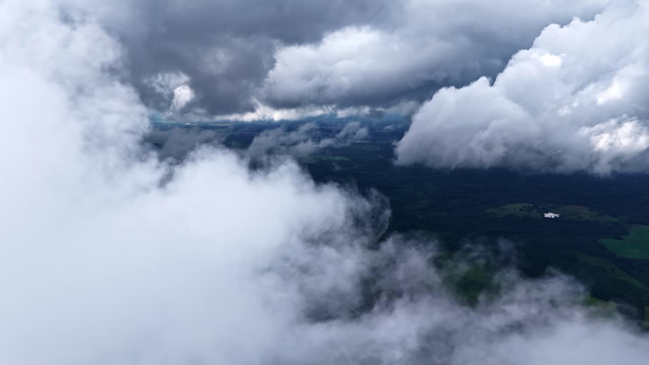 Aerial view of fluffy clouds drifting gently over a scenic landscape below